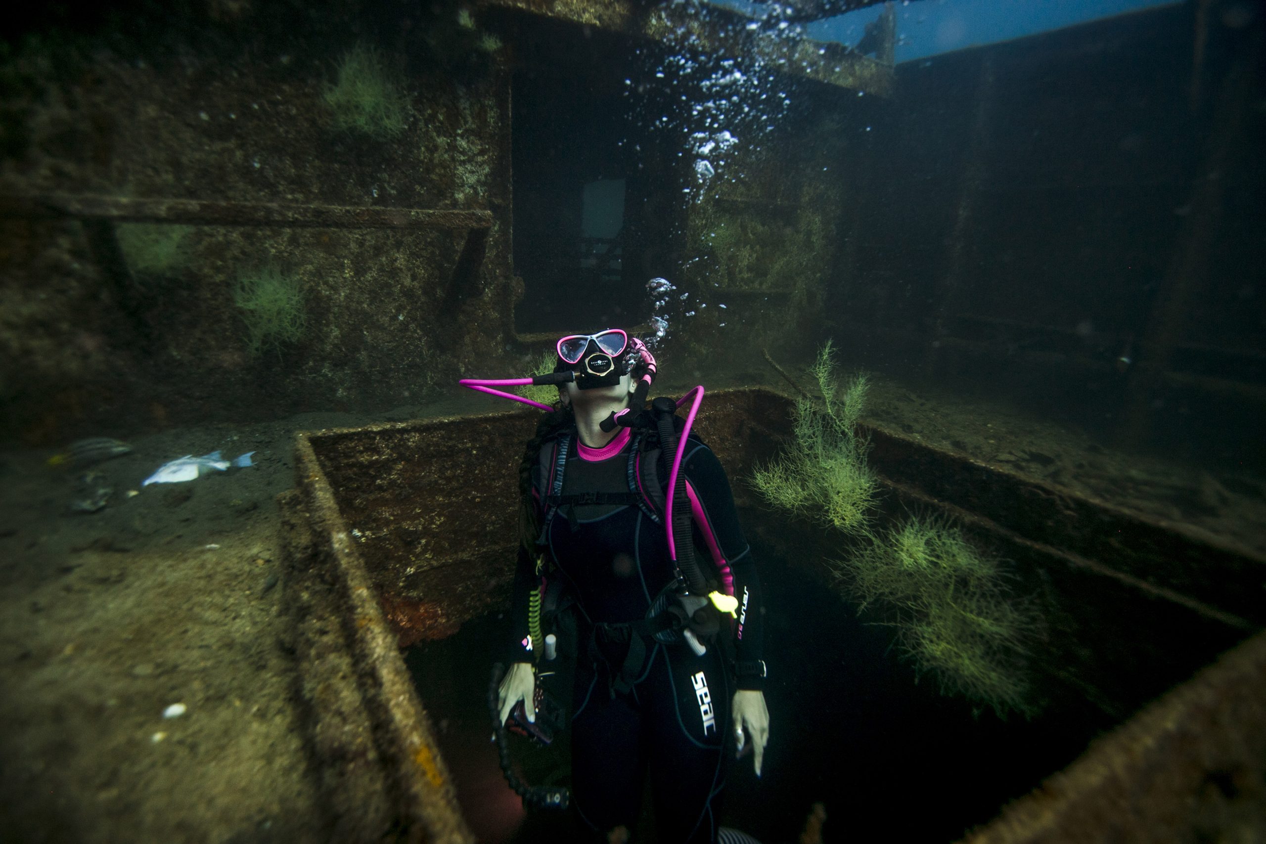 Junior Divemaster scuba diving through a shipwreck